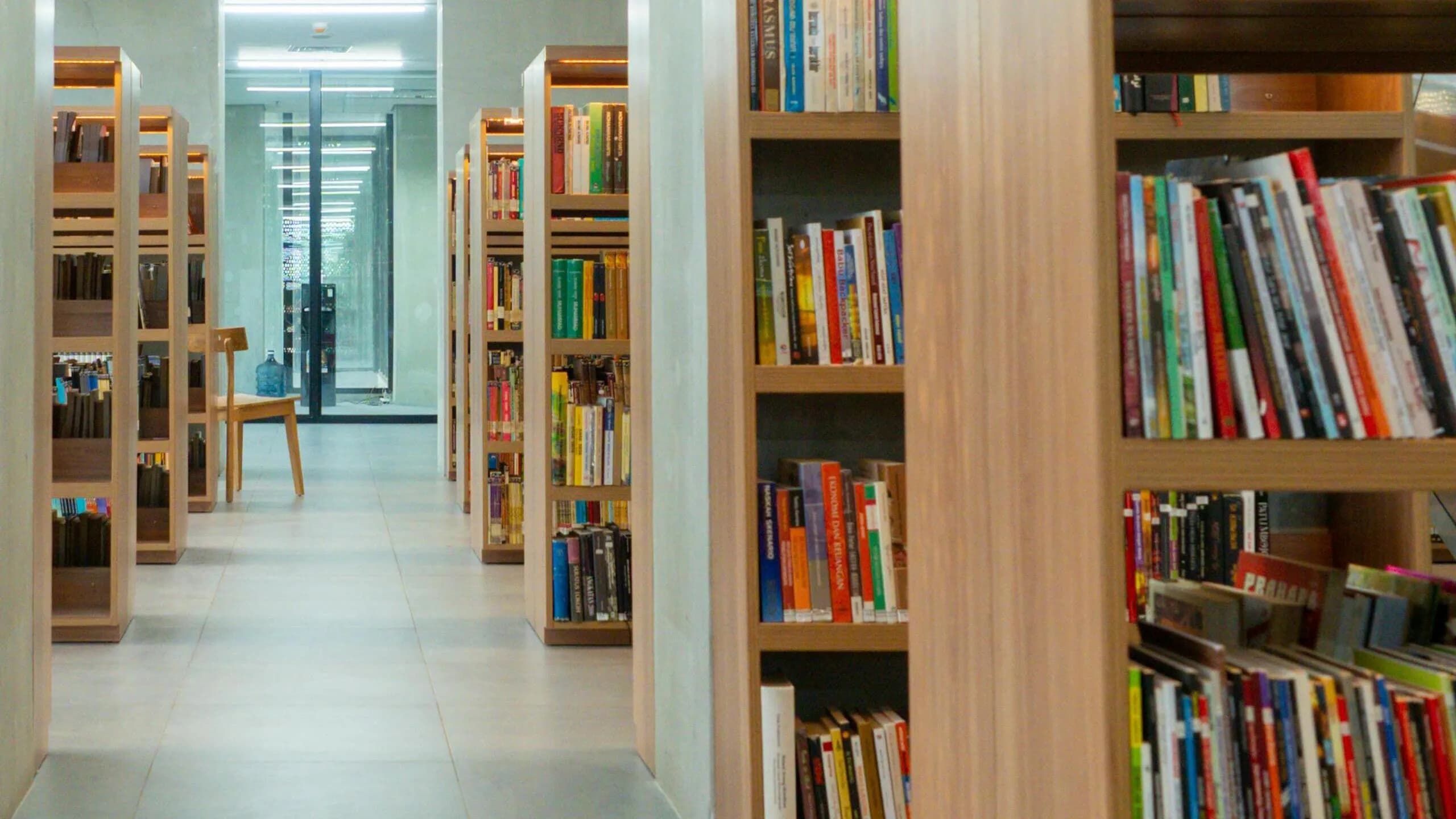 Rows of books lining the wooden shelves of a bright, modern library