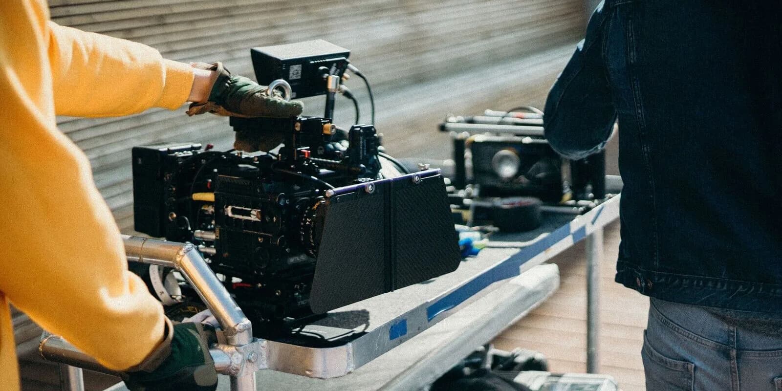 A film crew setting up a cinema camera on a rig at an outdoor location shoot