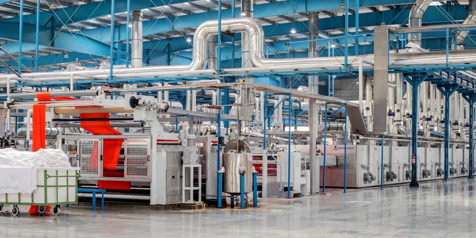 A manufacturing and production floor with machinery and overhead piping