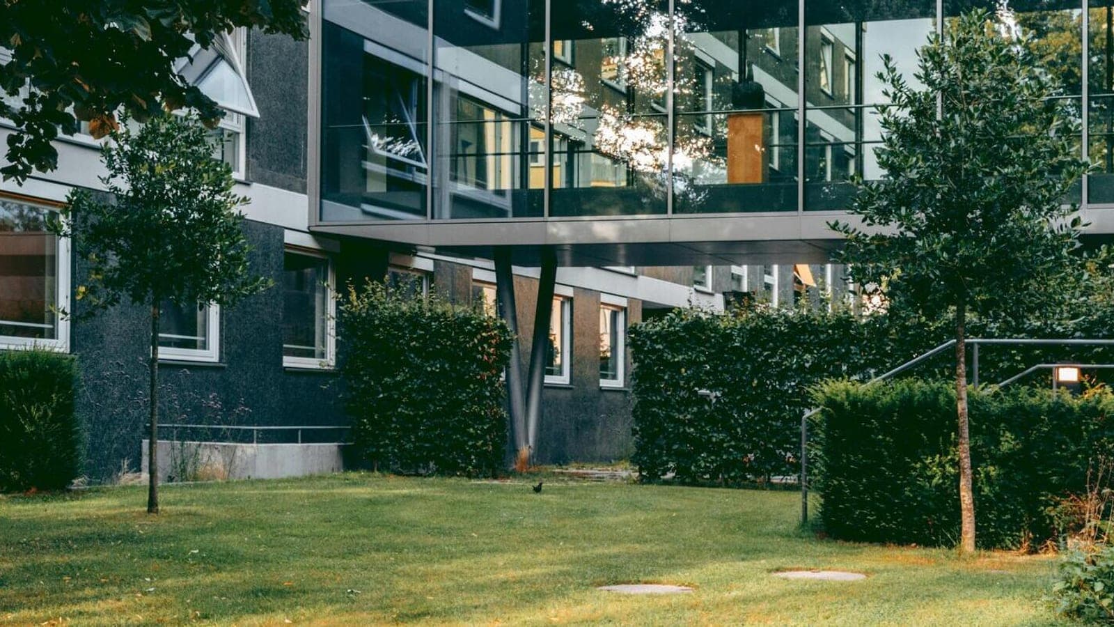A commercial office building with a manicured lawn and trimmed hedges