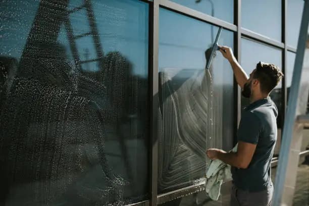 A window cleaner using a squeegee to clean a large commercial glass panel