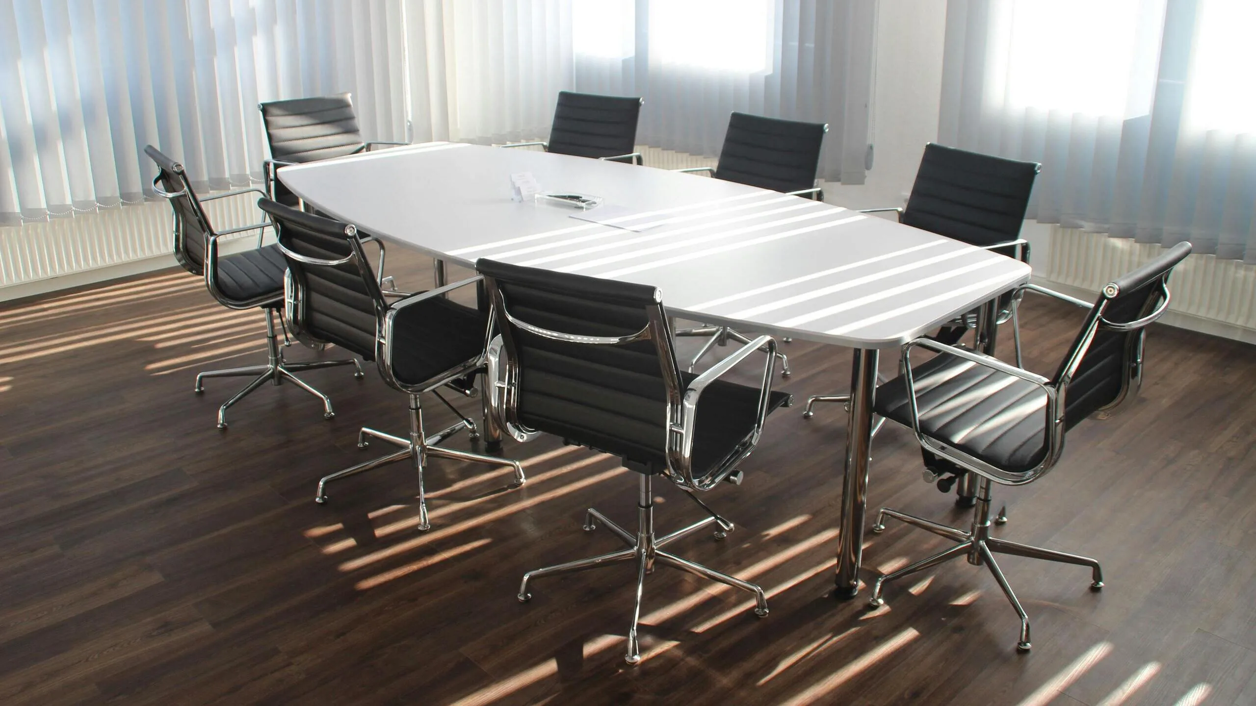 Clean office boardroom with conference table and chairs on hardwood floor