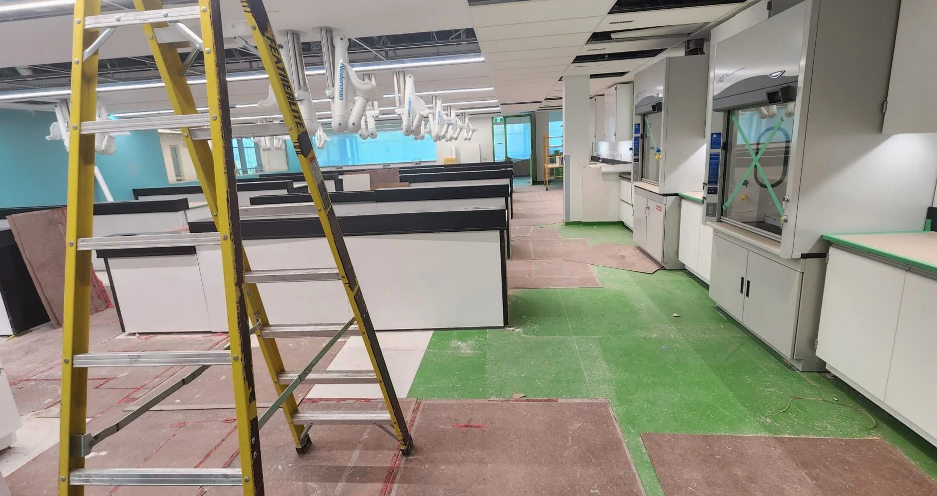 Construction site interior with ladder, dust and taped-off cabinetry